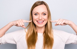 Woman pointing to a healthy smile. 