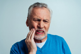 Man with denture sores rubs his jaw